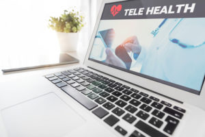 laptop with telehealth banner and photo of doctor