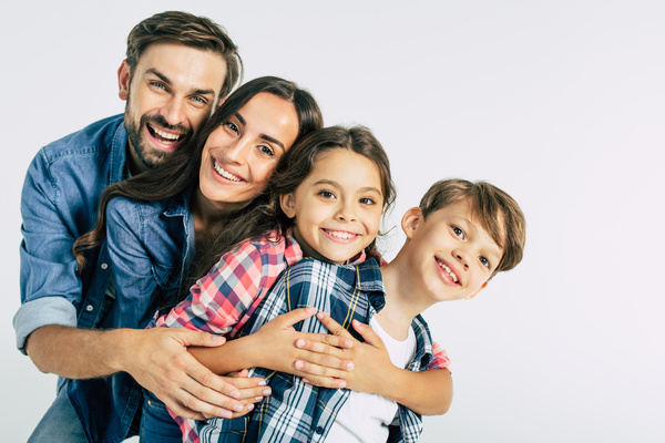 Family smiling for picture in front of white background