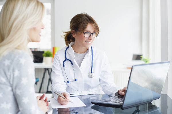 Doctor looking at computer with patient