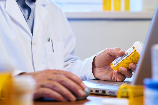 Person putting pills into hand from prescription bottle