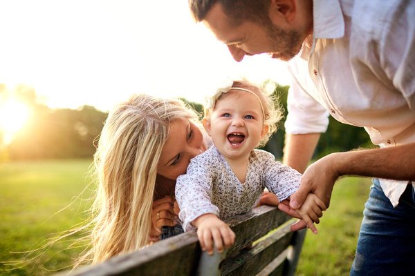 Couple with young happy girl playing on bench.